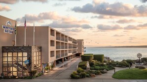 A hotel with a modern design, featuring a large building with multiple balconies, a well-maintained outdoor area with greenery, and a view of the water. - Monterey Bay Inn (Monterey)