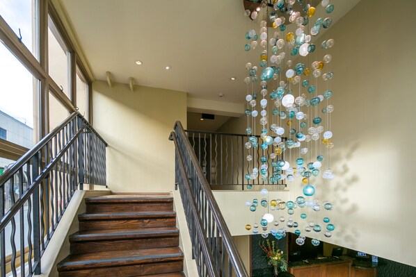 A staircase with wooden steps and metal railings, leading to a reception area with a desk and chairs.