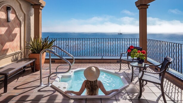 A balcony with a hot tub, seating, and a view of the sea. - Monterey Bay Inn (Monterey)