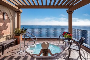 A balcony with a hot tub, seating, and a view of the sea. - Monterey Bay Inn (Monterey)