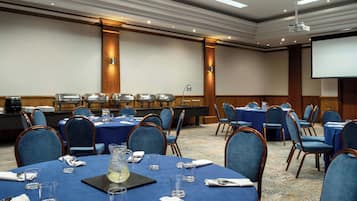 A conference room with round tables, blue tablecloths, and matching chairs.