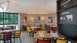 Un restaurante con paredes de ladrillo, mesas de madera y sillas de colores.