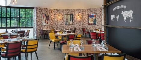 A restaurant with brick walls, wooden tables, and colorful chairs.