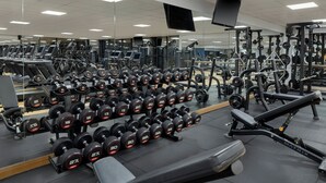 Un gimnasio con diversos equipos de ejercicio, incluyendo cintas de correr, mancuernas y máquinas de pesas.