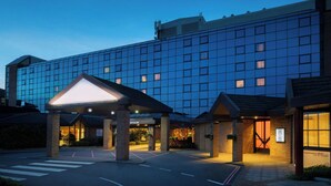 Un hotel moderno con fachada de vidrio, entrada cubierta y un cartel que indica WiFi gratuito.