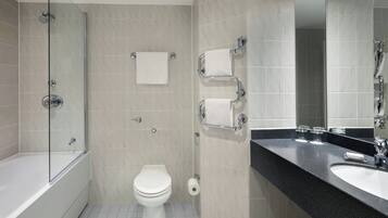 A modern bathroom with a glass-enclosed shower, a white toilet, and a black countertop with a sink and mirror.