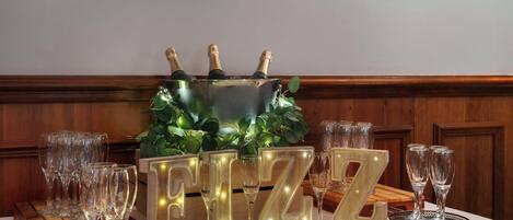 A table with champagne bottles, glasses, and illuminated letters spelling "FIZZ".