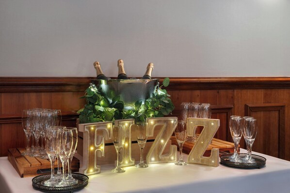 A table with champagne bottles, glasses, and illuminated letters spelling "FIZZ".