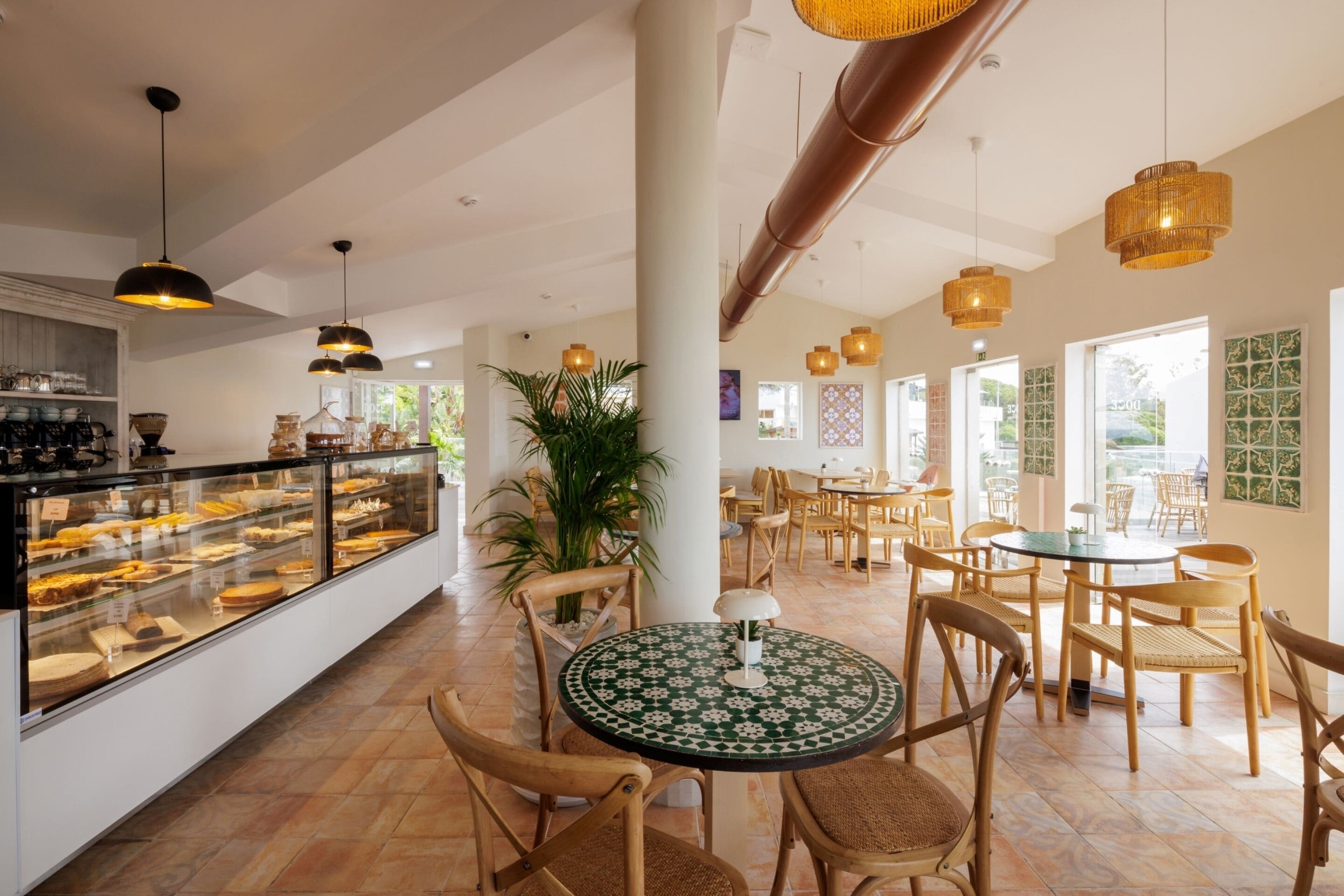Un restaurante con una vitrina de vidrio, sillas de madera y lámparas colgantes.