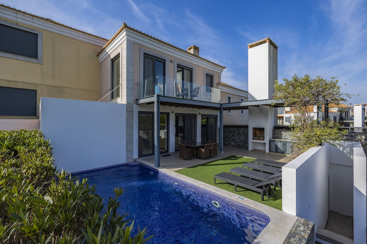 A modern house with a swimming pool, outdoor furniture, and a covered patio area.