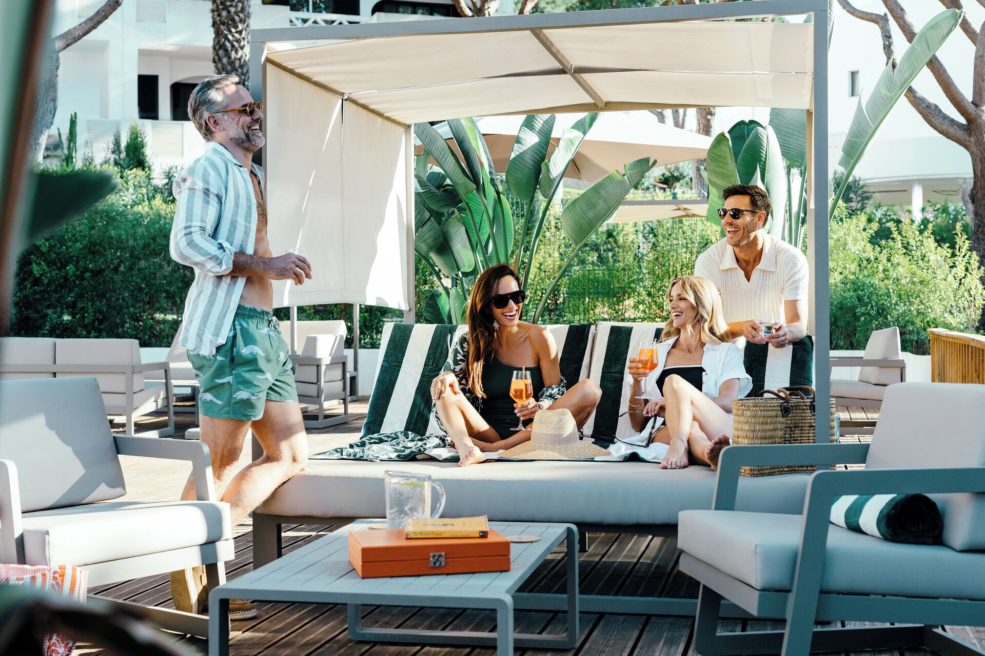 Un espace patio avec des sièges extérieurs, une table avec des boissons et un coin salon abrité.