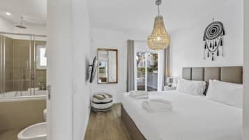 A modern hotel room with a large bed, a shower, a vanity, and a view of the outdoors.