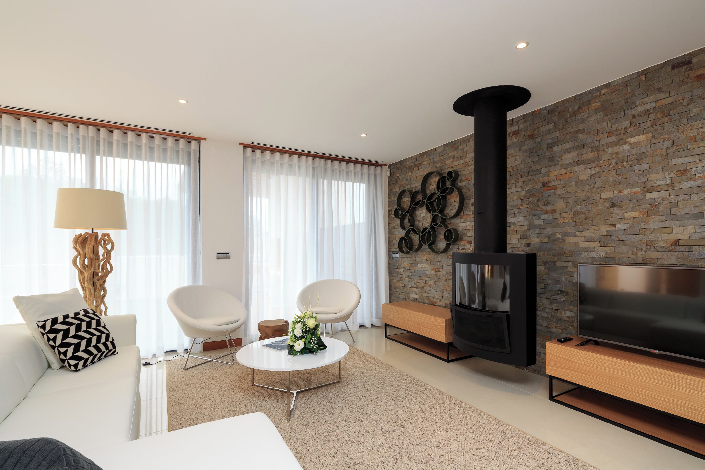 Un salon moderne avec une cheminée, des meubles blancs et un mur d’accent en briques.