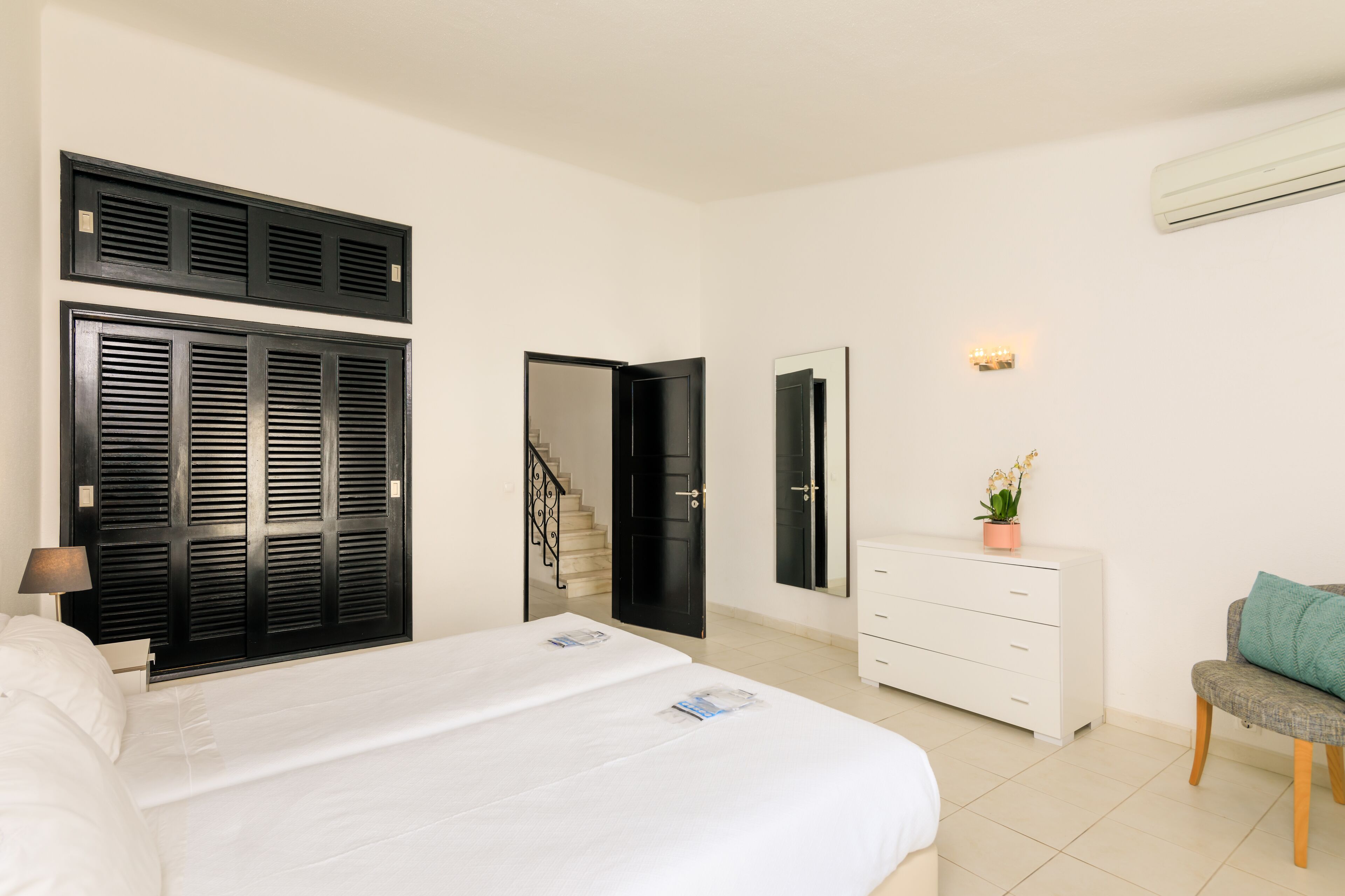 Een hotelkamer met een groot bed, een kaptafel, een spiegel en een trap naar een andere kamer.