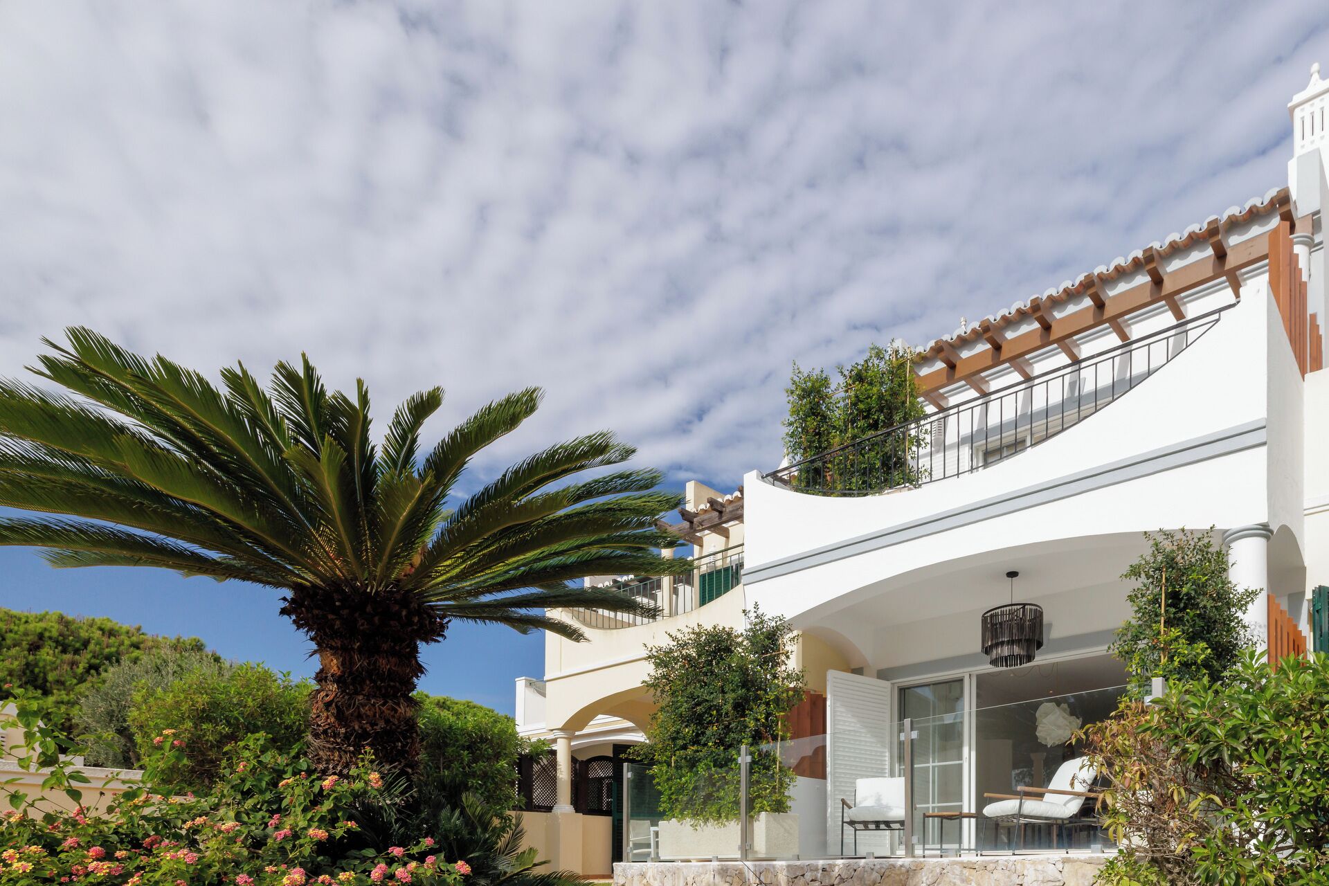 Una casa moderna de dos pisos con un balcón, una palmera y un jardín.