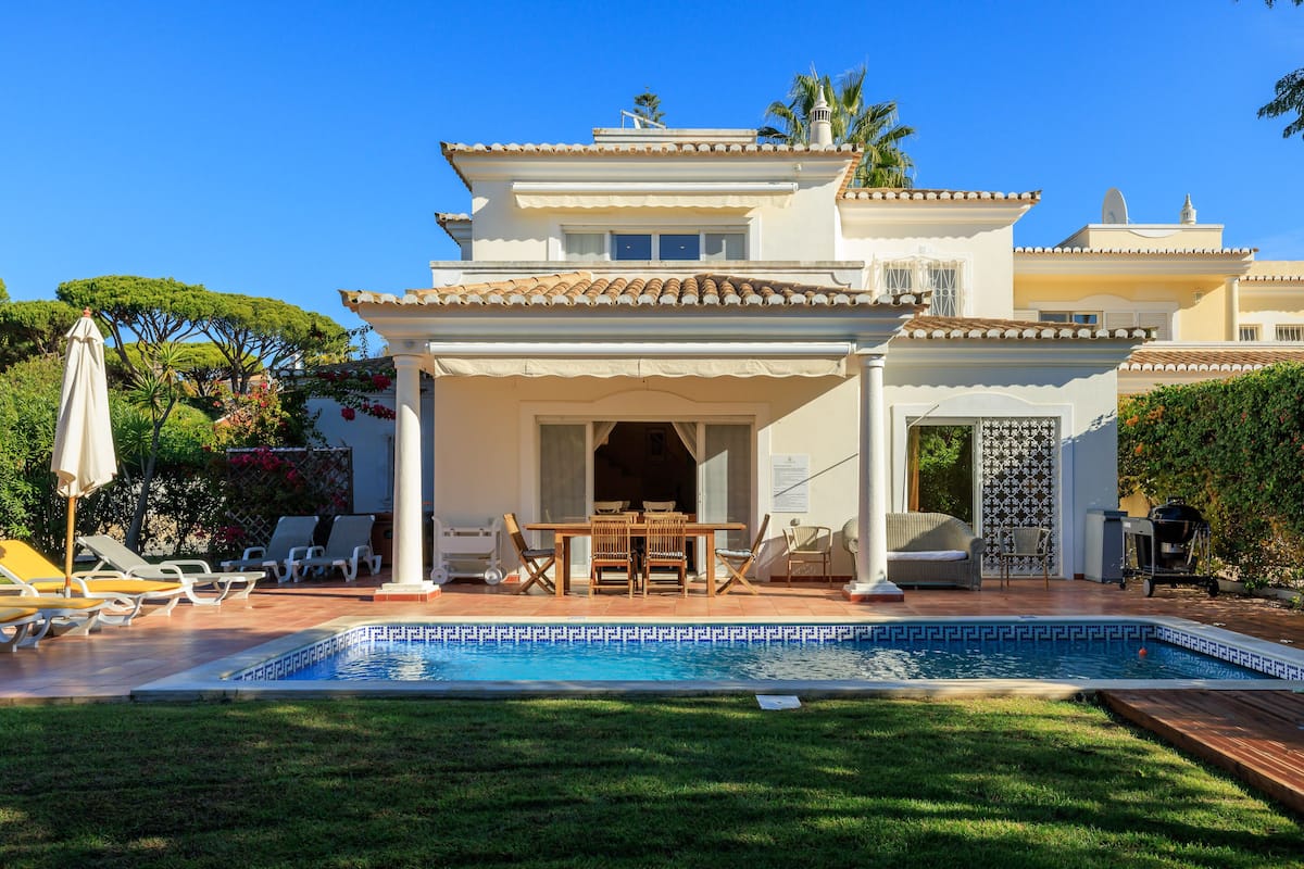 A two-story house with a swimming pool, outdoor seating, and a covered patio area.
