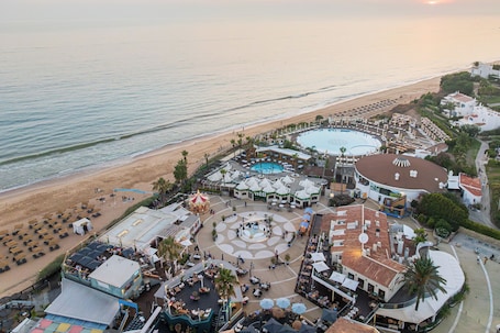 An aerial view of a resort with a beach, a pool, and various dining and leisure areas.. Vale do Lobo Resort