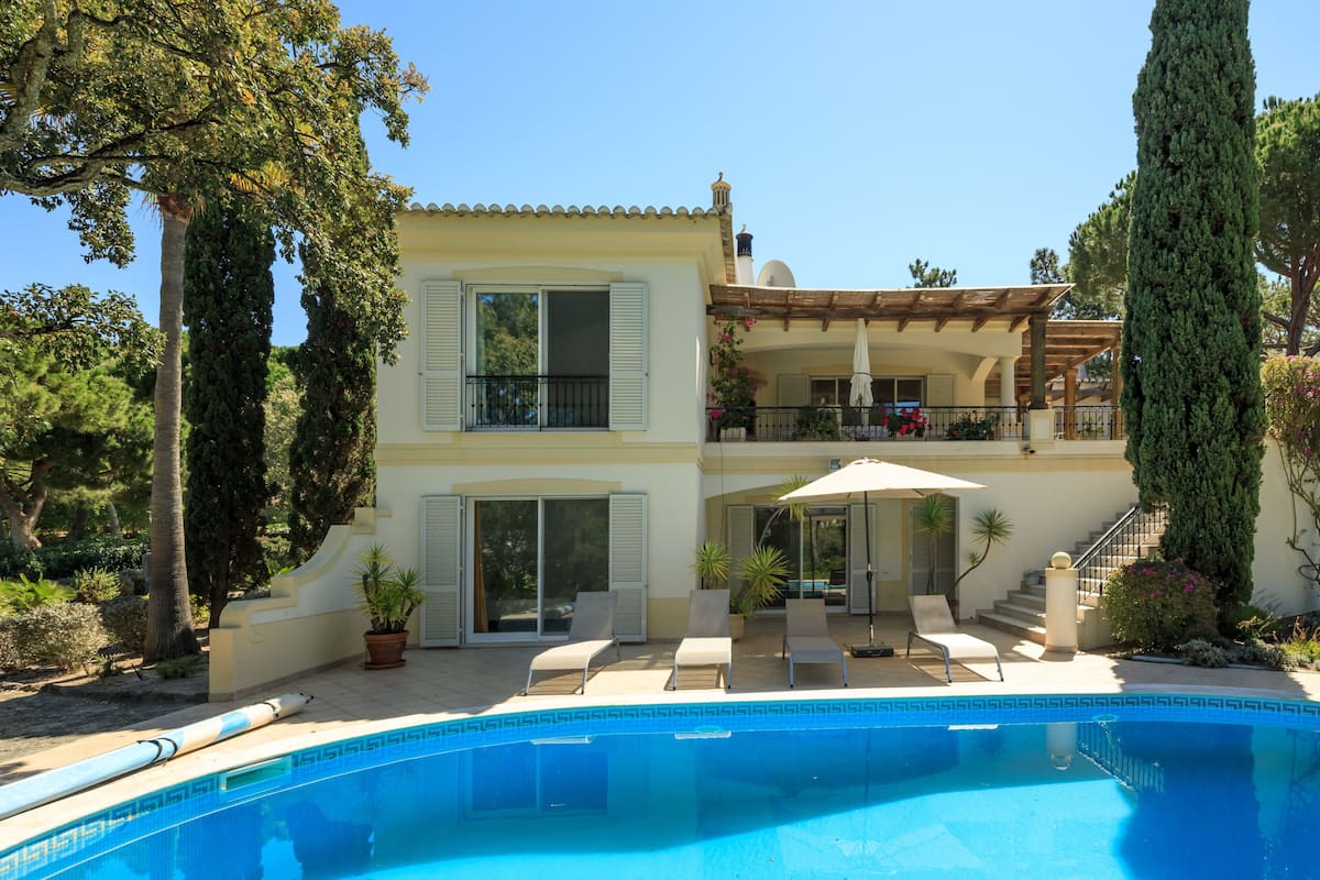 A two-story house with a swimming pool, outdoor seating, and a covered patio.