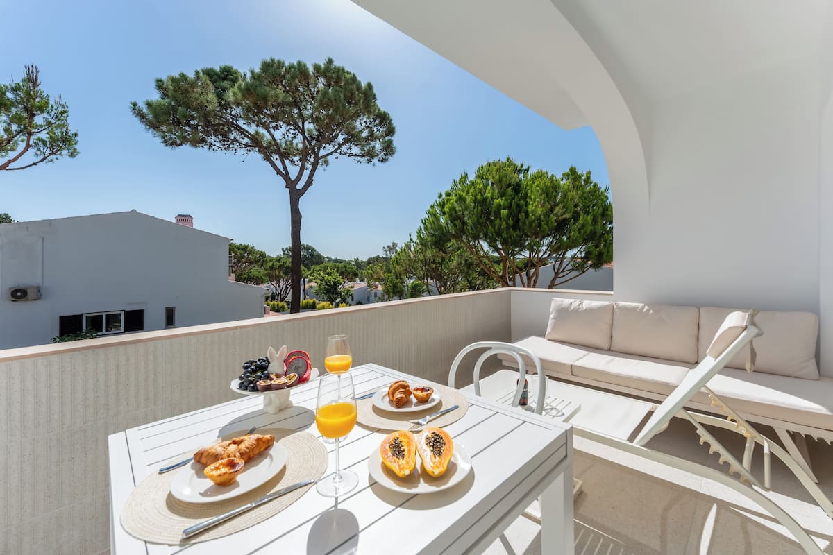 A balcony with a table set for breakfast, including croissants, fruit, and orange juice.