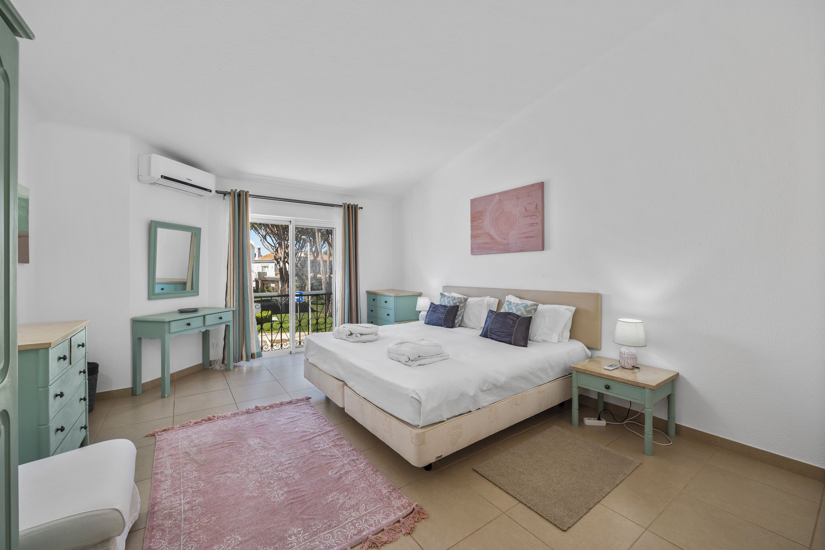 Un dormitorio con cama, mesitas de noche, escritorio y silla.