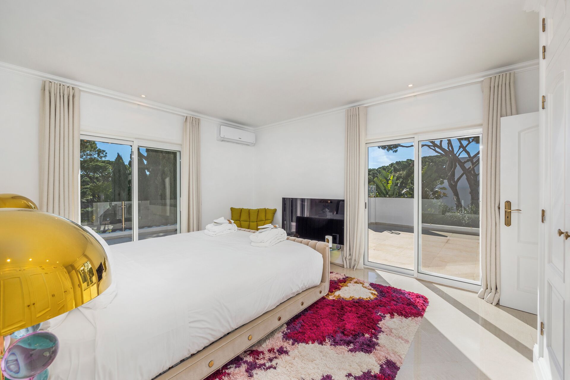 Une chambre moderne dotée d’un grand lit, d’un téléviseur à écran plat et offrant une vue sur l’extérieur grâce à de grandes portes coulissantes.