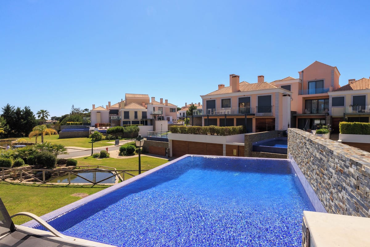 A swimming pool with a stone wall and a view of modern buildings.