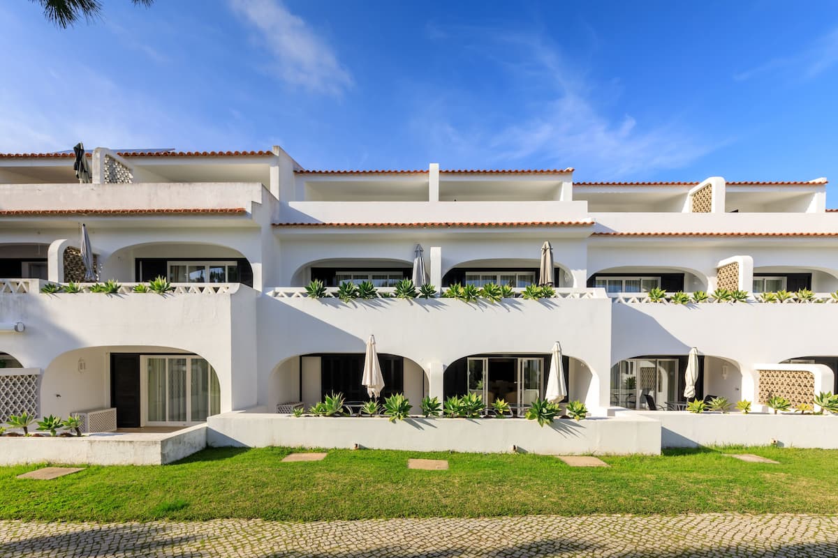 A white building with multiple balconies, covered walkways, and outdoor seating areas.