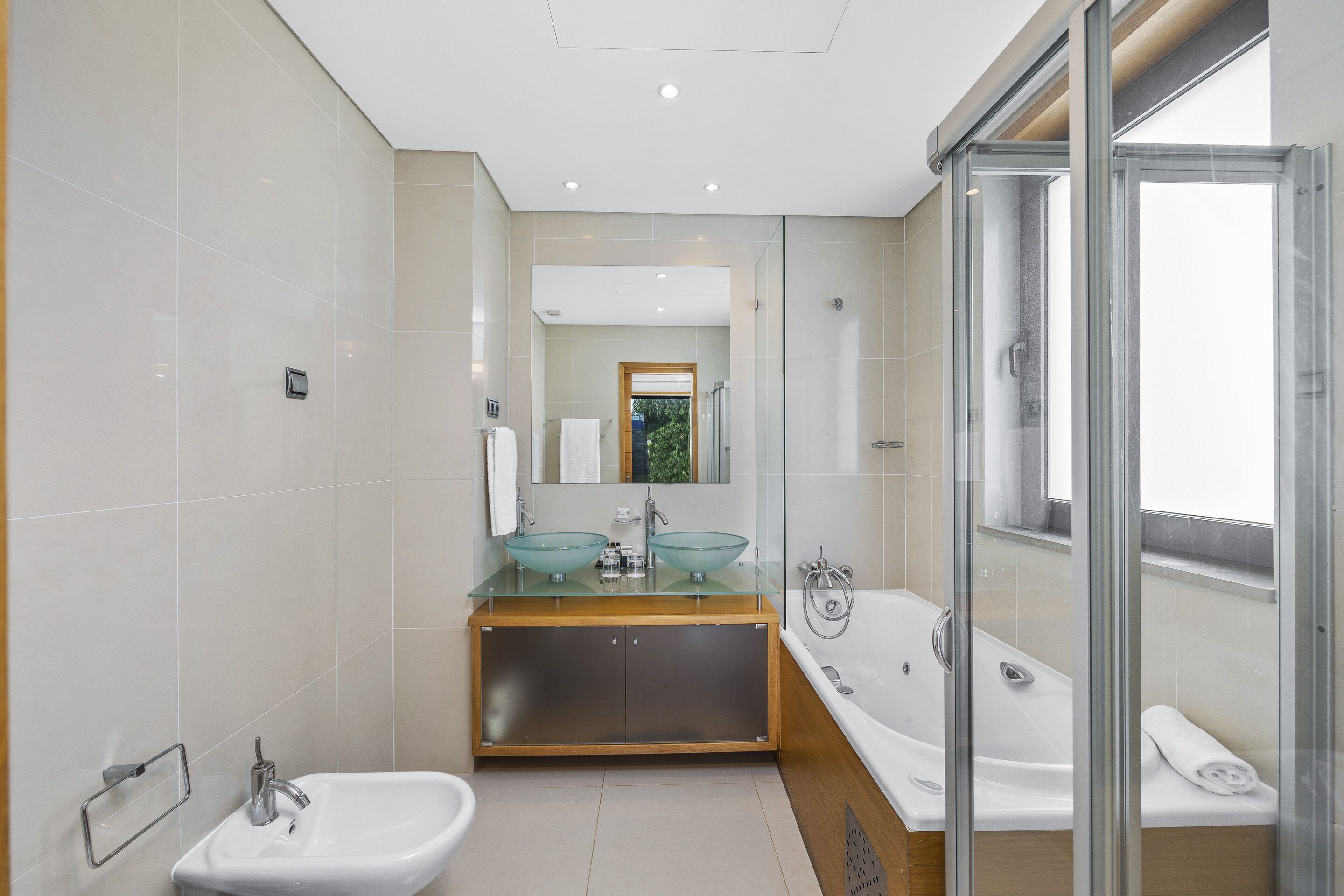 A modern bathroom with a glass-enclosed shower, a double sink vanity, and a bathtub.