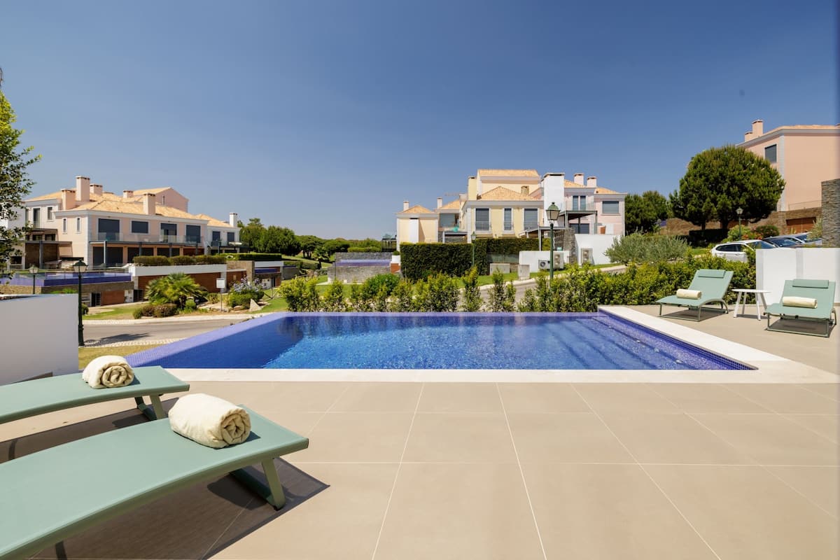 A swimming pool with lounge chairs and a view of residential buildings.