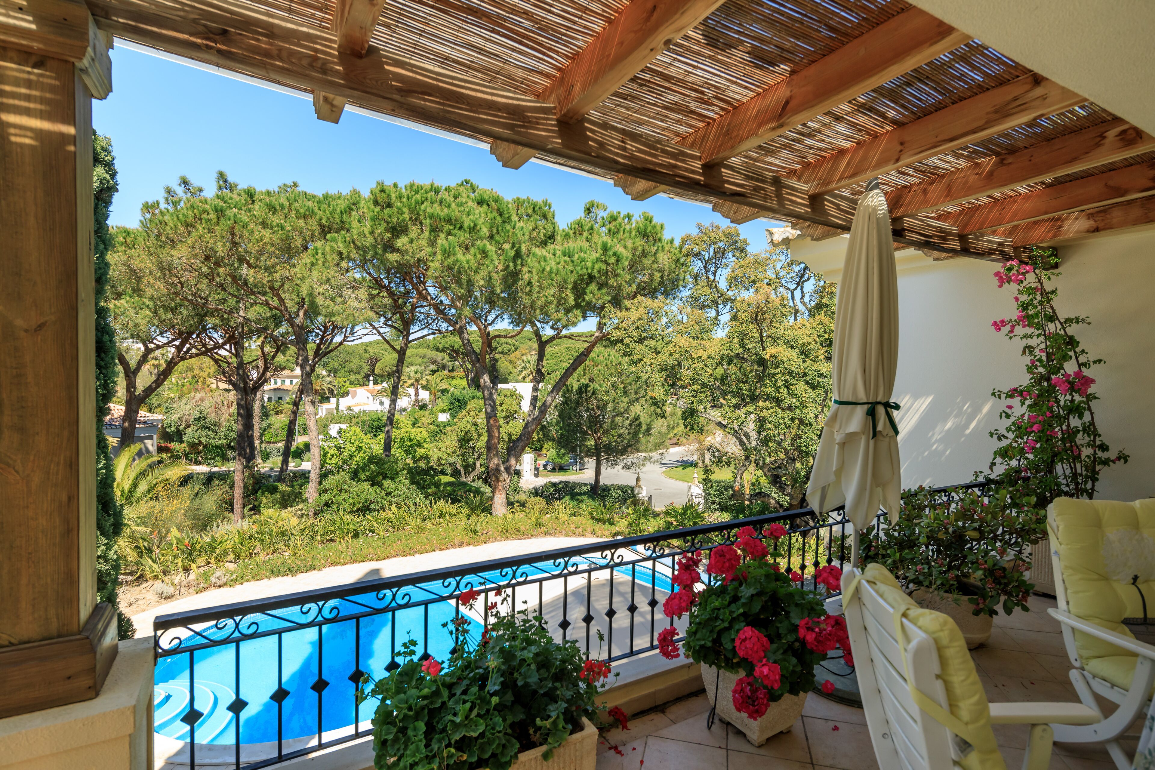 Ein Balkon mit Blick auf Bäume und ein Schwimmbad.