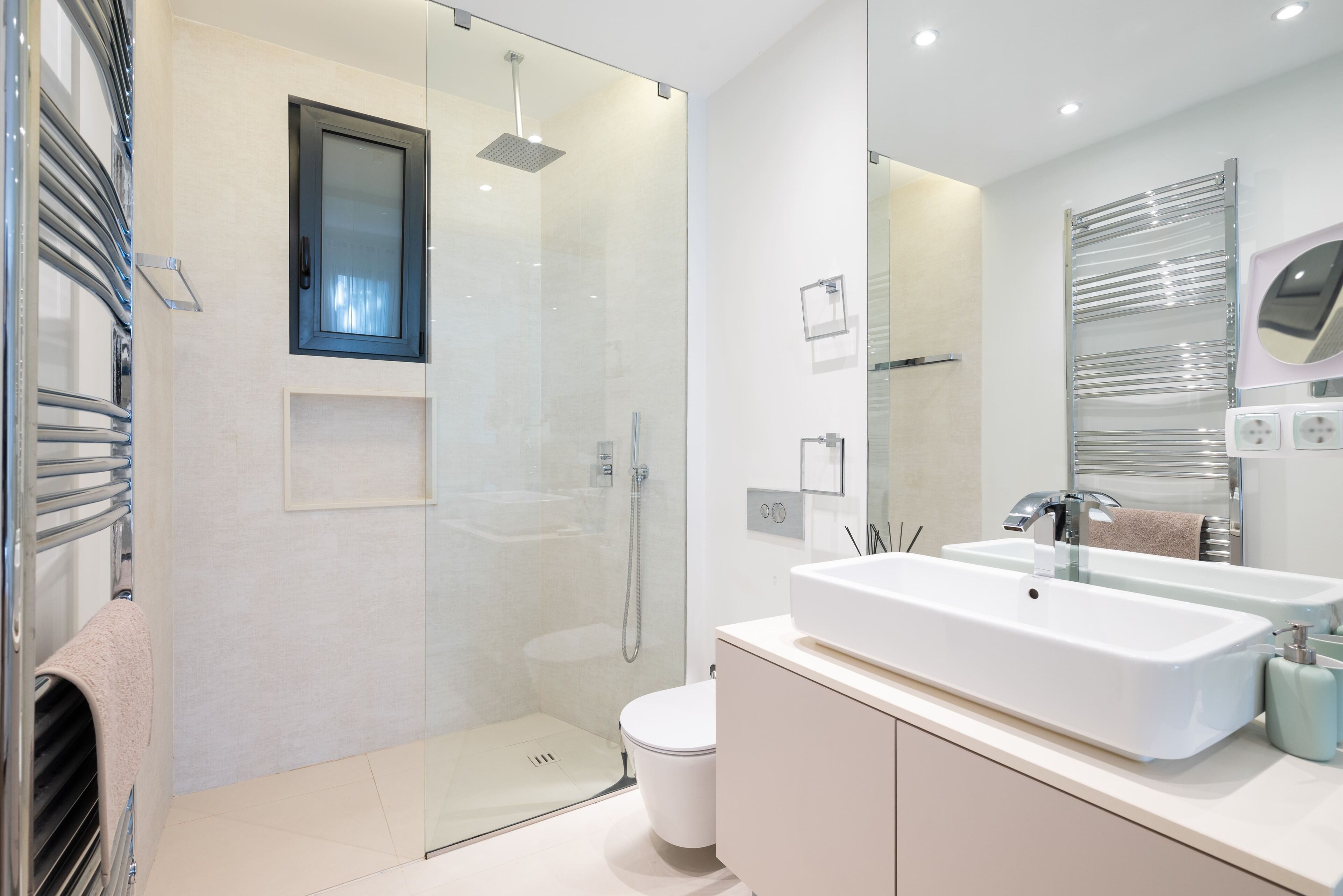A modern bathroom with a glass shower enclosure, a white sink with a mirror, and a toilet.