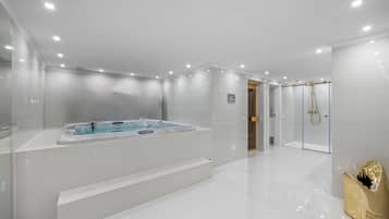 A modern bathroom with a large bathtub, a shower area, and a glass-enclosed toilet.