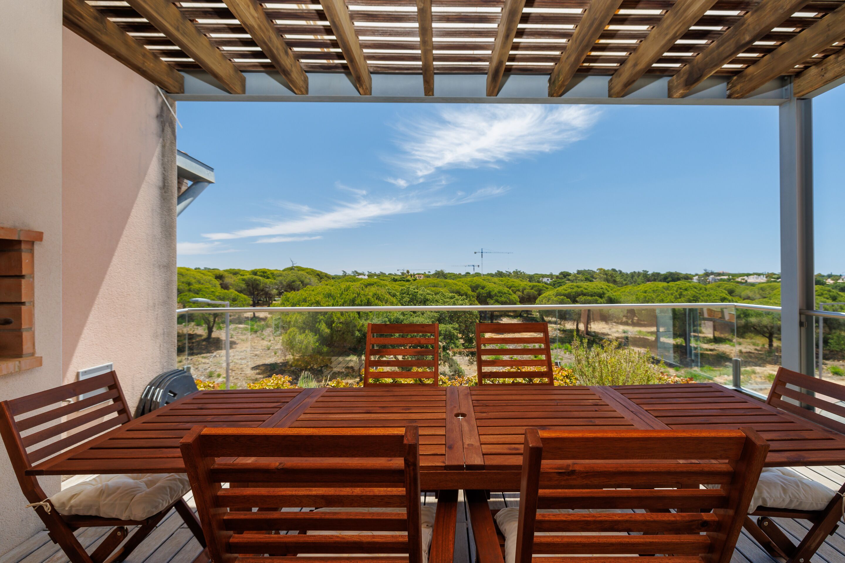 Un conjunto de mesa y sillas de madera en un balcón con una vista despejada del paisaje.