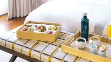 Una bandeja de desayuno ordenada sobre la cama, con una almohada, una botella y un vaso de zumo de naranja.
