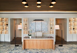 A reception area with a marble-top desk, two floor lamps, and shelves with decorative items.