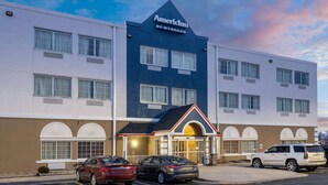 A hotel with a prominent 'American' sign, a central entrance with a red roof, and multiple parking spaces. - AmericInn by Wyndham Cedar Rapids North (Cedar Rapids)