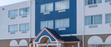 A hotel with a blue and beige facade, a central entrance with a small porch, and multiple windows.