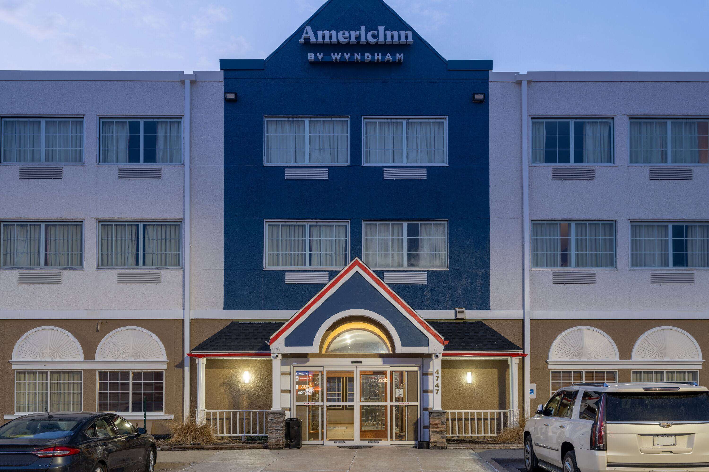 A hotel with a blue facade, a central entrance with a red and white trim, and multiple windows.