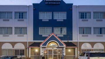 A hotel with a blue facade, a central entrance with a red and white trim, and multiple windows.