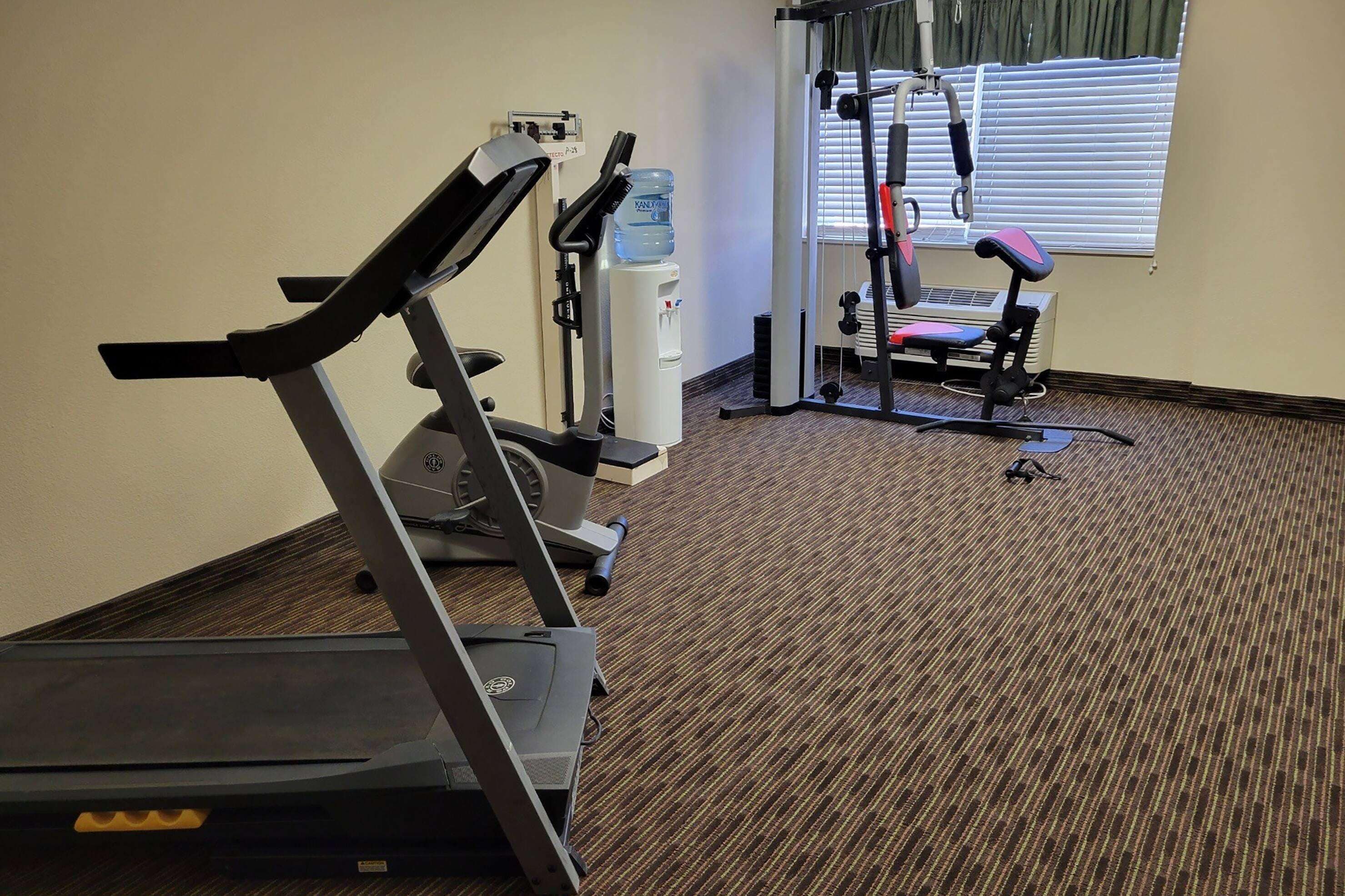 A gym with a treadmill, water dispenser, and exercise equipment.