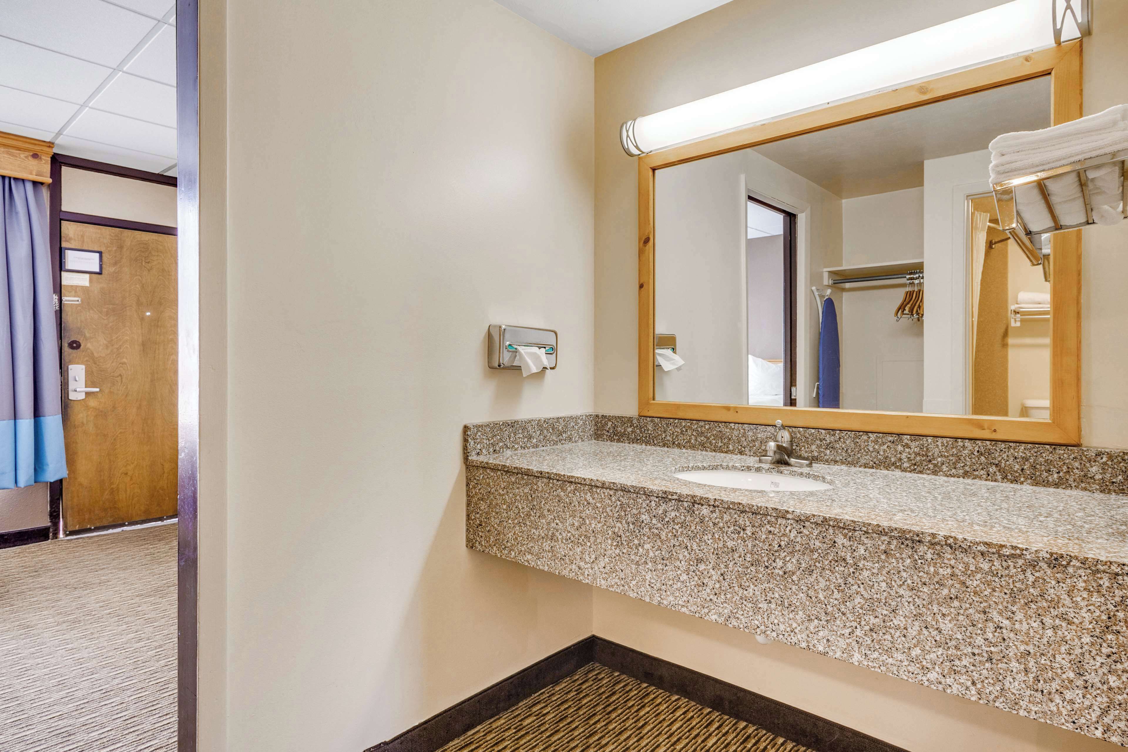 A bathroom with a granite countertop sink, a mirror, and a towel rack.