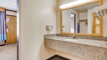 A bathroom with a granite countertop sink, a mirror, and a towel rack.