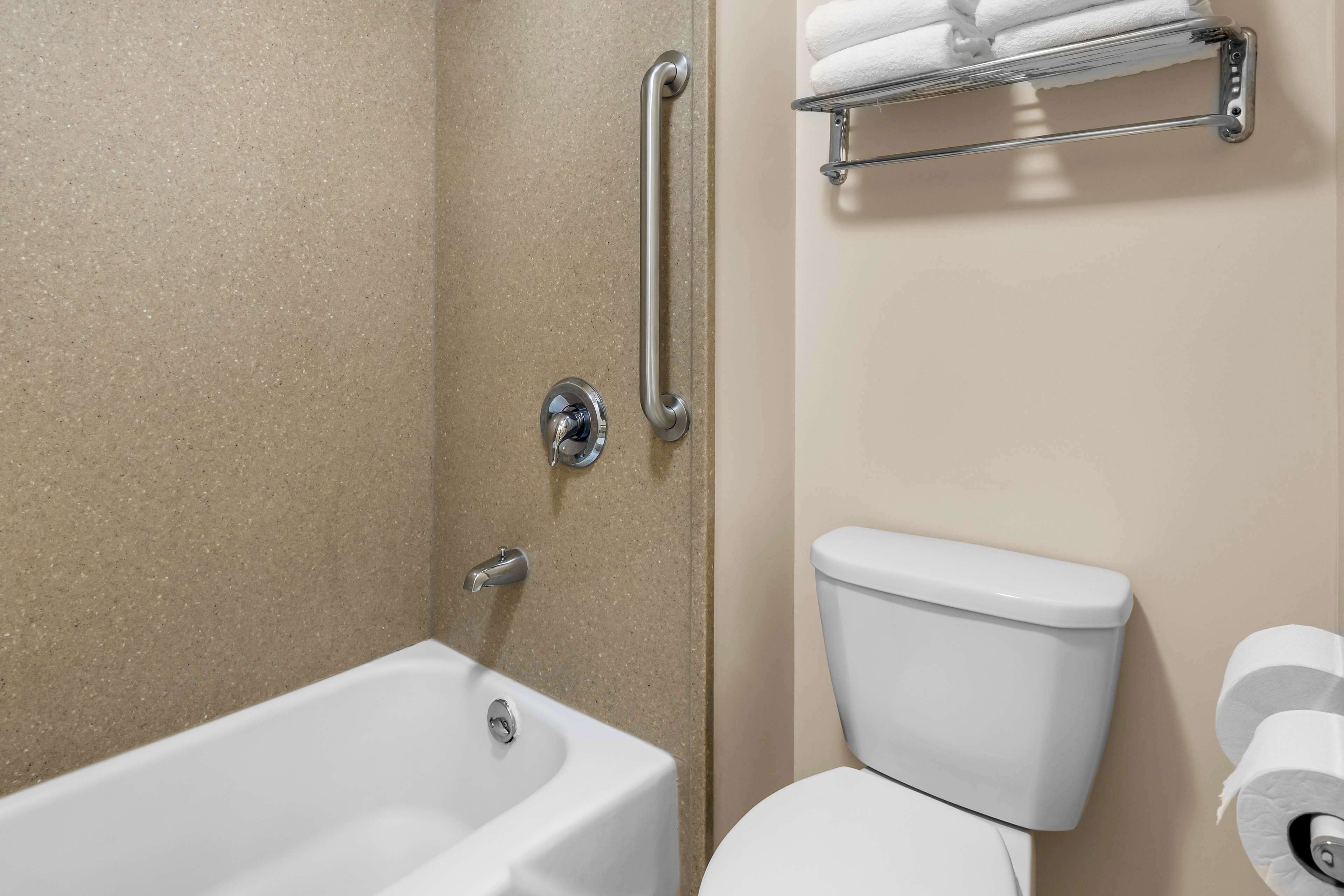 A bathroom with a bathtub, toilet, and a towel rack.