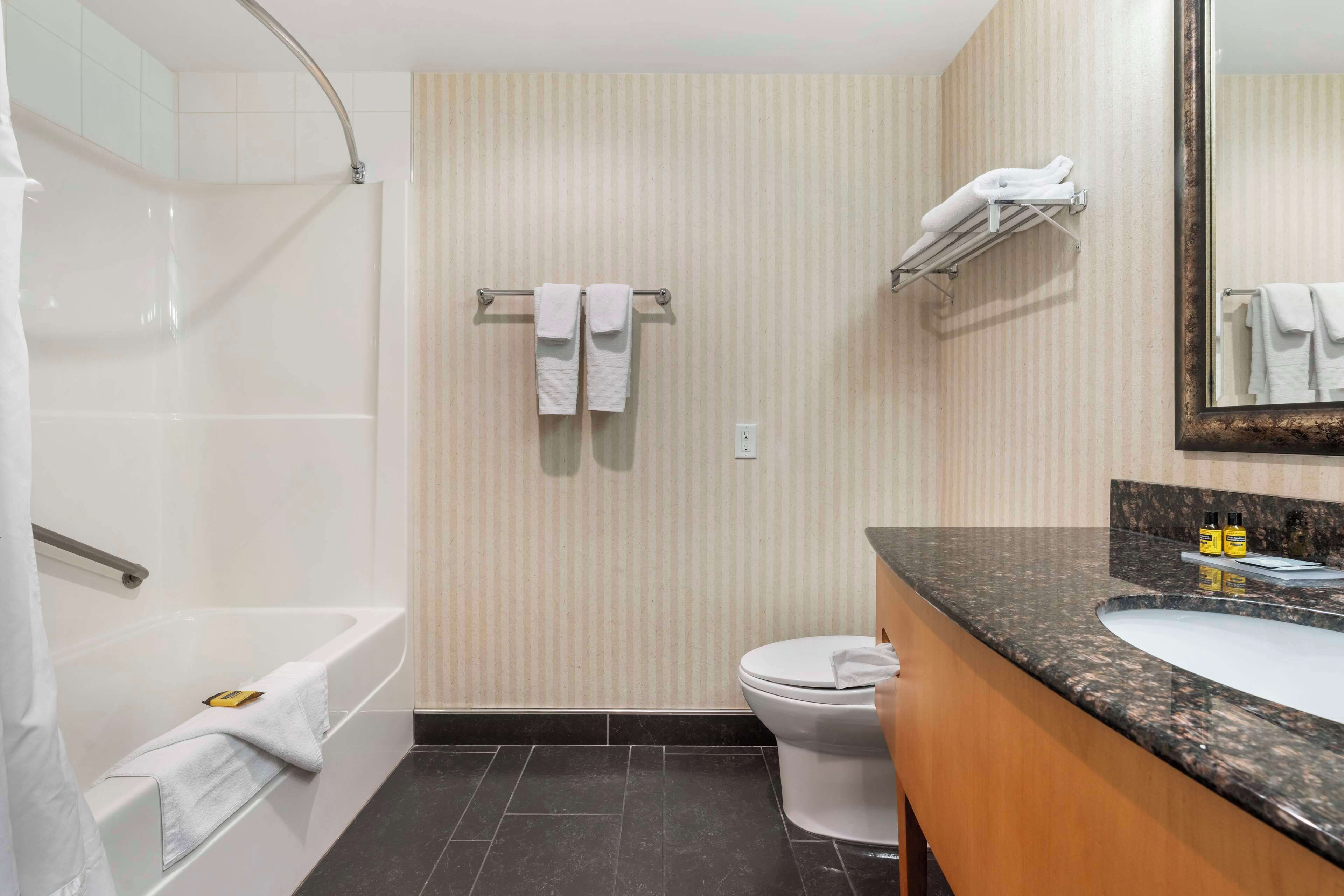 A modern bathroom with a bathtub, toilet, and vanity with a sink.