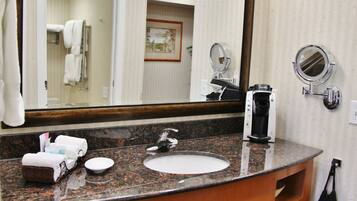 Une salle de bain avec un comptoir en granit, un lavabo, un miroir et un porte-serviettes.