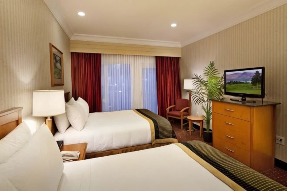 Une chambre d’hôtel avec deux lits, une télévision, un bureau et une chaise.