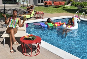 A swimming pool area with lounge chairs, a red table with a fruit bowl, and inflatable toys. - ibis Styles Abidjan Marcory (Abidjan)