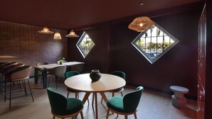 Un comedor moderno con mesas redondas, sillas verdes e iluminación colgante.