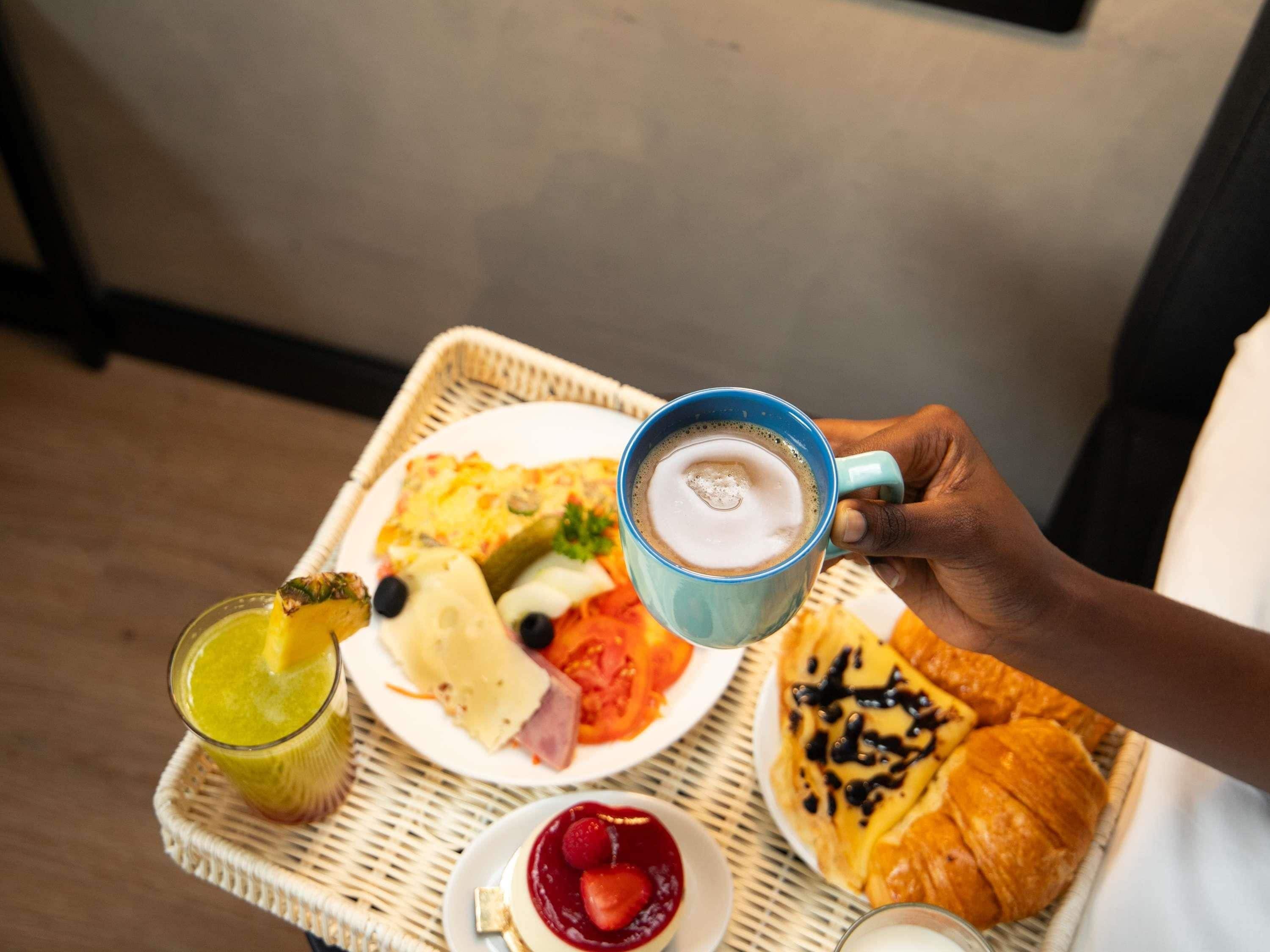 Una bandeja con alimentos para el desayuno, como huevos, tostadas, un croissant, un vaso de jugo y una taza de café.