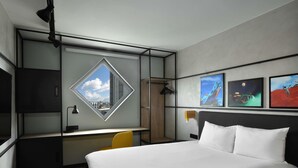 Una habitación de hotel moderna con cama, escritorio y un amplio ventanal.